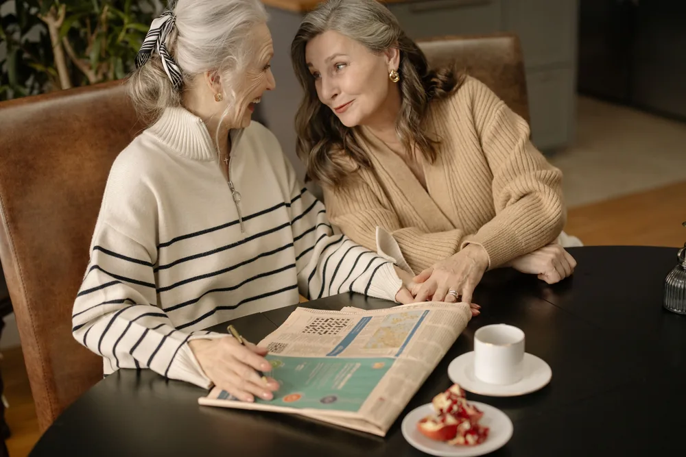Two adults laughing over a puzzle at a kitchen table