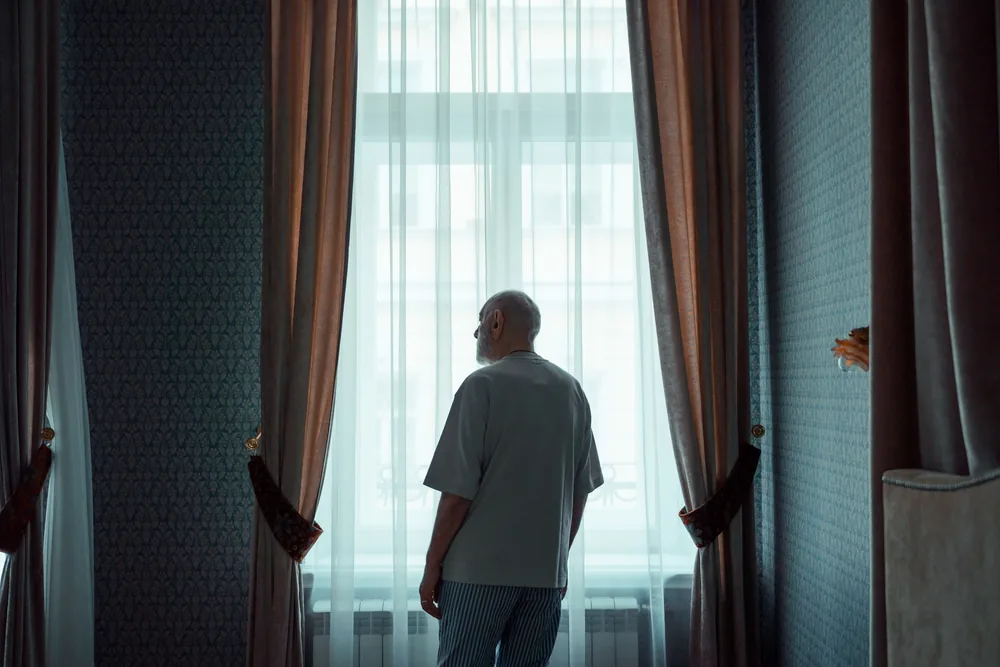 A man looking thoughtfully out of a window