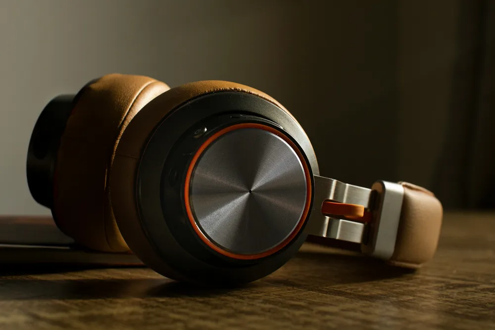 A pair of over-ear headphones resting on a wooden table in warm light