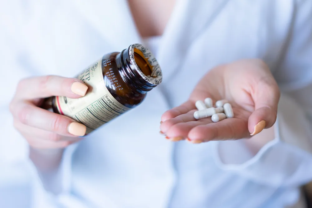 A woman reading the label on a supplement bottle
